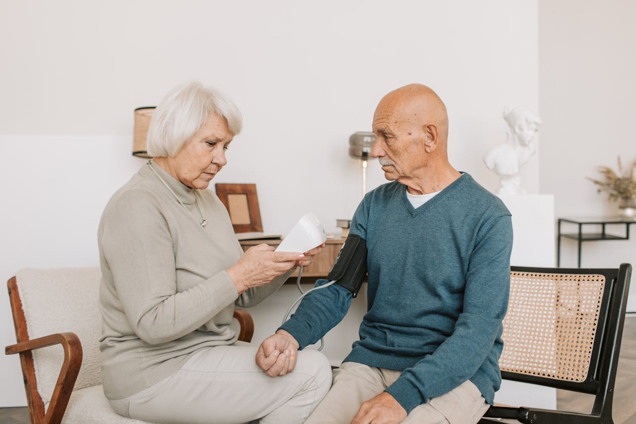 gallery-01 Senior couple measuring blood pressure at home, showcasing care and companionship.
